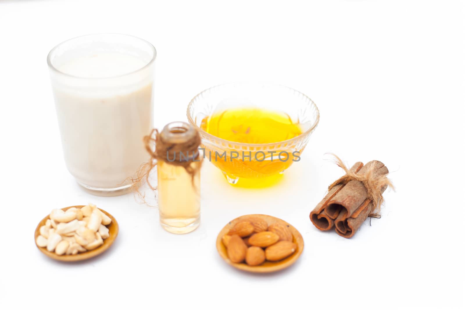 Close up of popular Indian &amp; Asian winter drink isolated on white i.e Honey milk or shahad ka dudh in a transparent glass with entire ingredients which are milk,honey, and dry fruits.