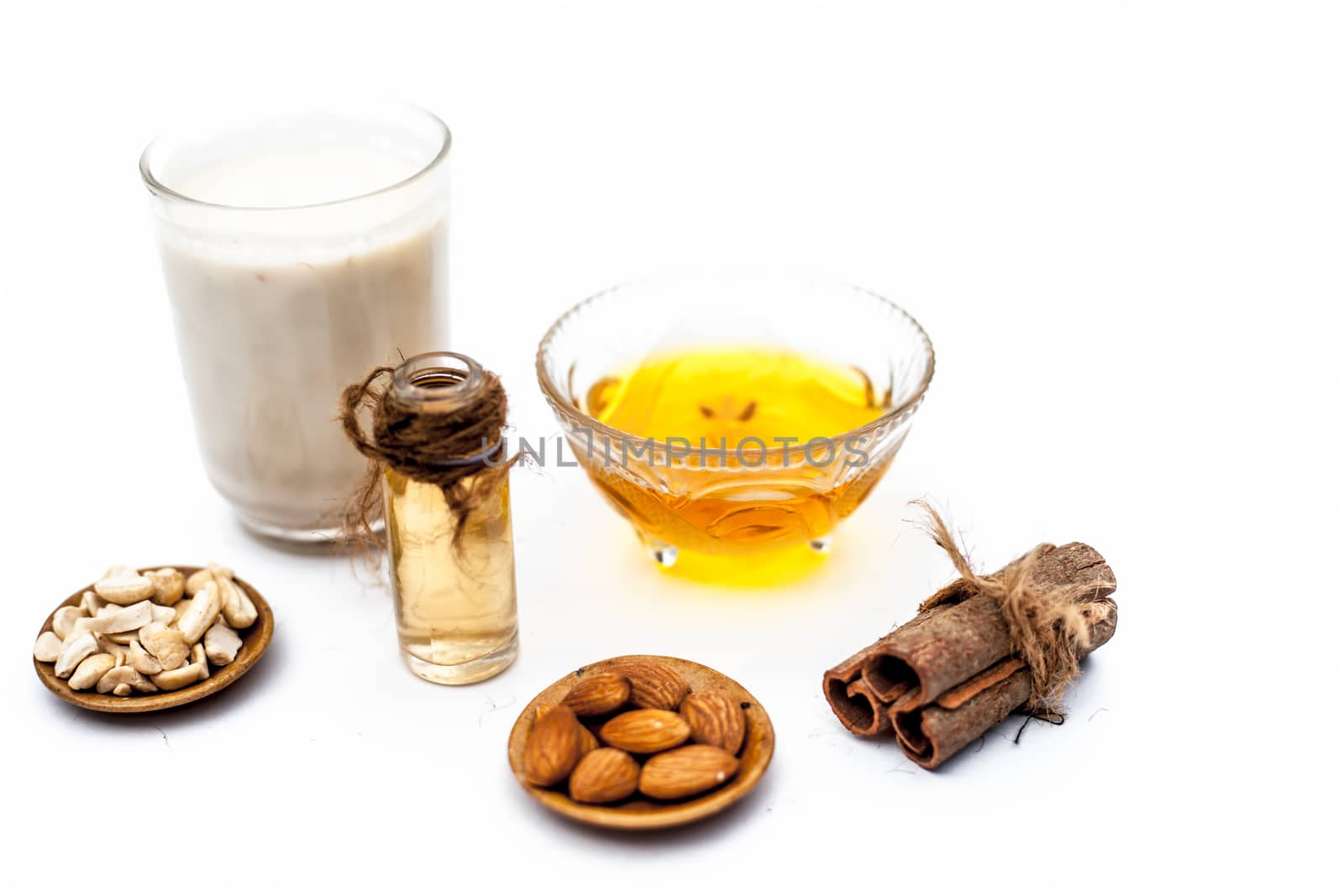 Close up of popular Indian &amp; Asian winter drink isolated on white i.e Honey milk or shahad ka dudh in a transparent glass with entire ingredients which are milk,honey, and dry fruits.