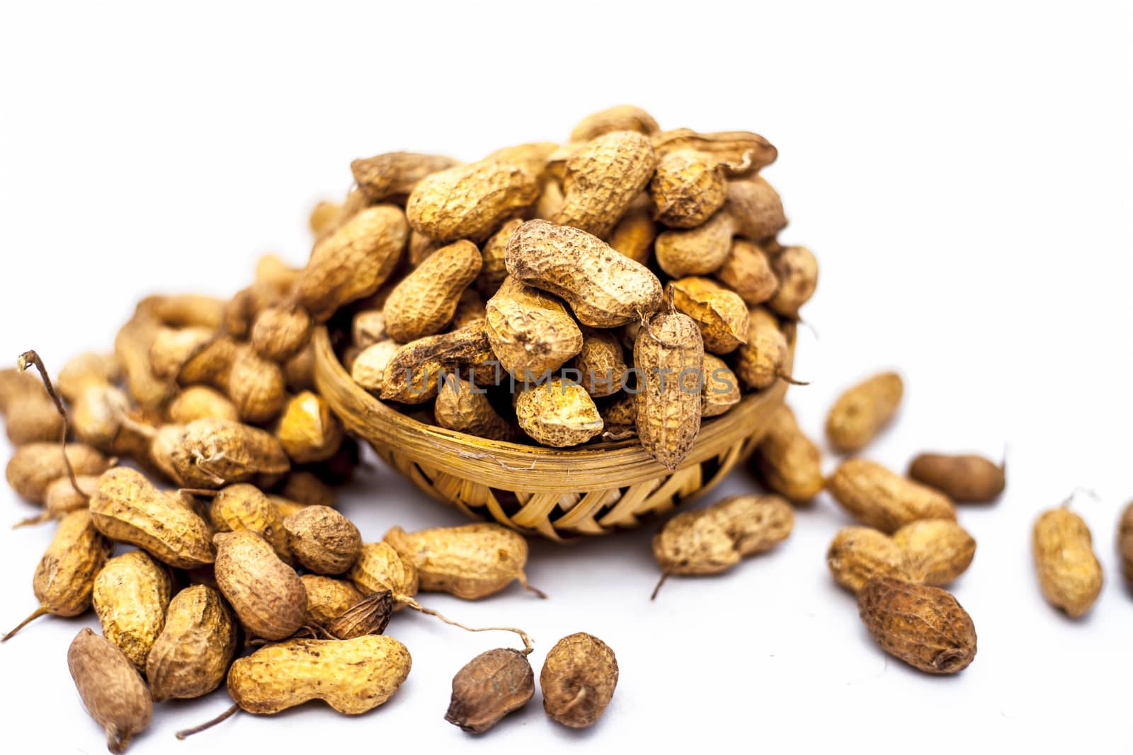 Close up of brown colored hamper having groundnuts or peanuts or moongaphalee or Arachis hypogaea or goober or monkey nut isolated on white.