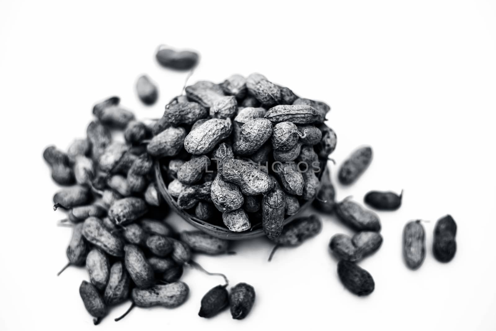 Close up of brown colored hamper having groundnuts or peanuts or moongaphalee or Arachis hypogaea or goober or monkey nut isolated on white.