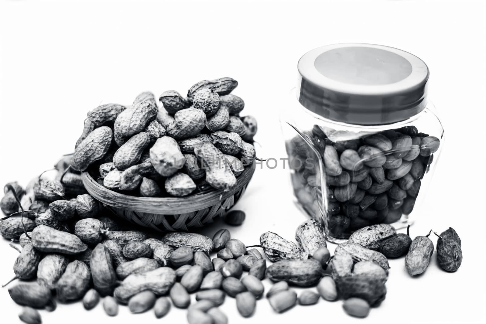 Close up of raw peanuts or groundnut isolated on white with some peeled in a separate bottle. by mirzamlk