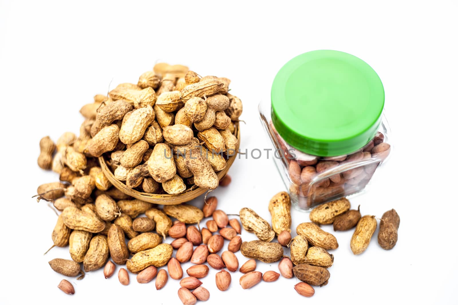 Close up of raw peanuts or groundnut isolated on white with some peeled in a separate bottle. by mirzamlk