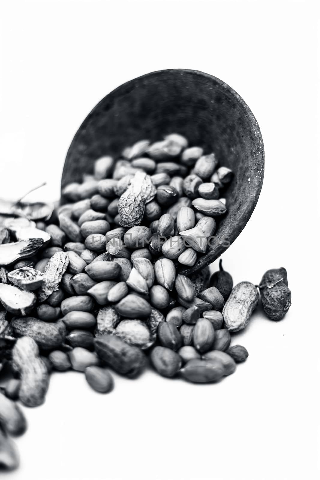 Raw organic groundnut or peanuts isolated on white with raw peanuts in a hamper with peanuts in clay bowl.