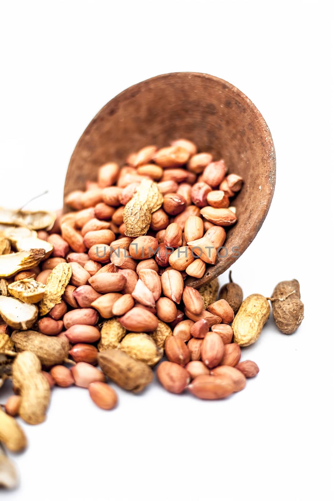 Raw organic groundnut or peanuts isolated on white with raw peanuts in a hamper with peanuts in clay bowl.
