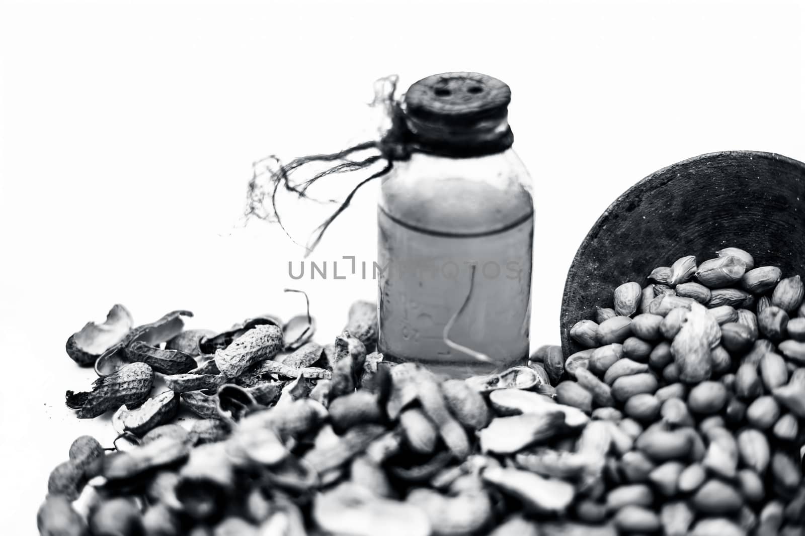 Close up of raw organic peanuts or ground nuts isolated on white along with its herbal organic extracted oil in a transparent bottle.