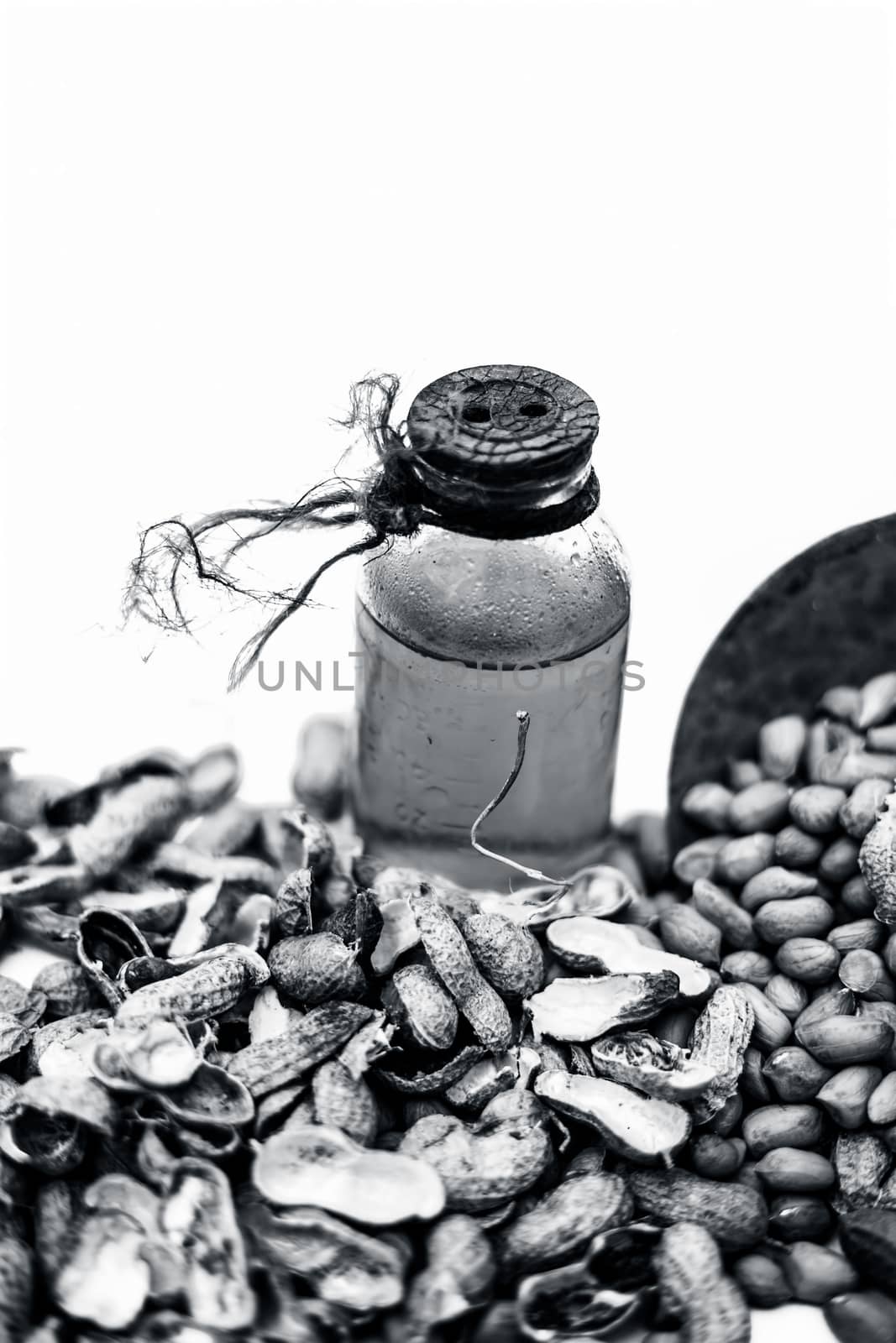 Close up of raw organic peanuts or ground nuts isolated on white along with its herbal organic extracted oil in a transparent bottle.