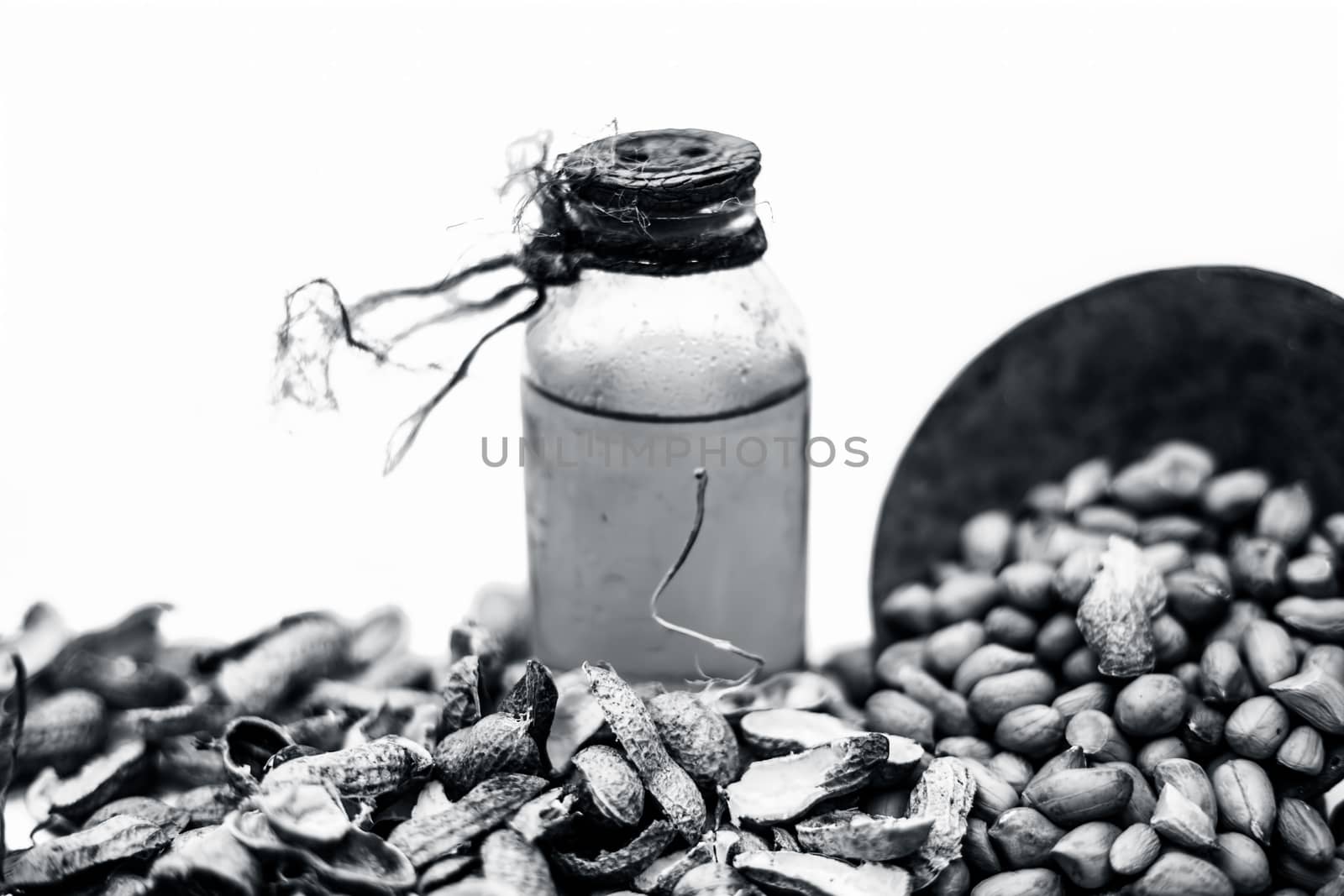 Close up of raw organic peanuts or ground nuts isolated on white along with its herbal organic extracted oil in a transparent bottle. by mirzamlk