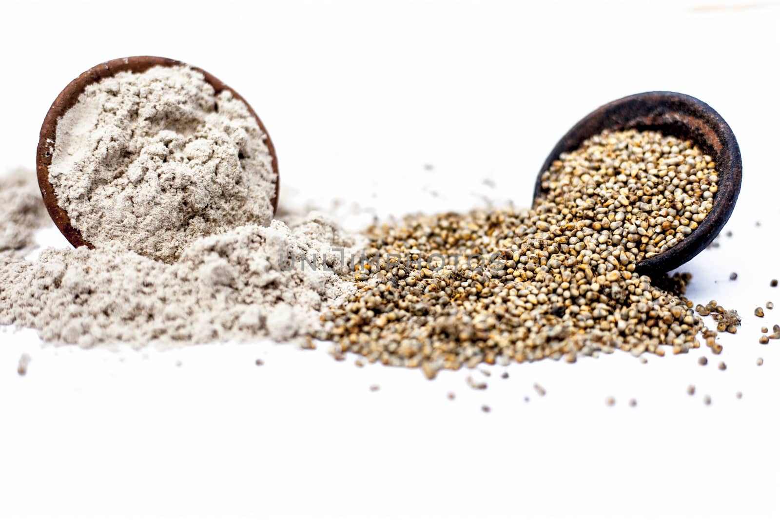 Close up of clay bowl of barley or pearl millet with its flour in a another bowl isolated on white.