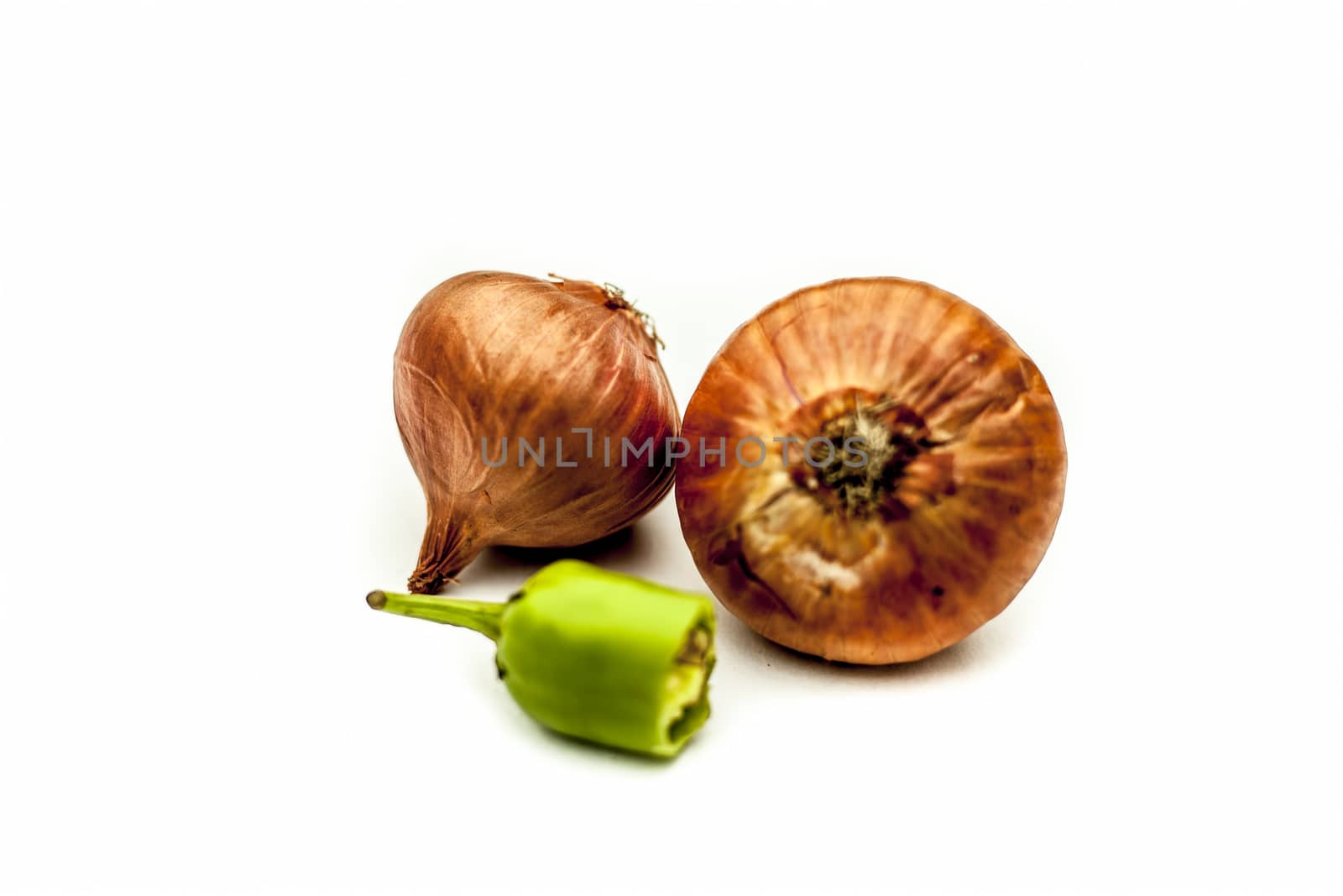 Raw organic two vegetables isolated on white which are onion or pyaaj or pyaaz along with cut chili or hari mirchi or lili mirchi.