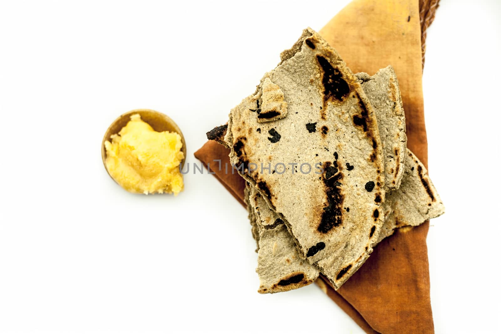 Close up of common or main ingredients of Malida isolated on white which are rot or bajri ki roti with jaggery in a small glass plate.