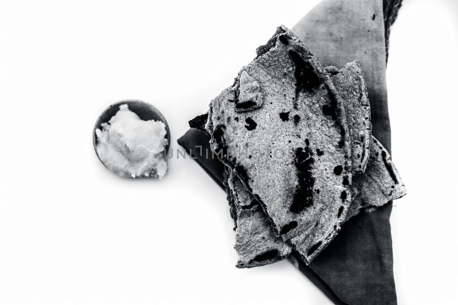 Close up of common or main ingredients of Malida isolated on white which are rot or bajri ki roti with jaggery in a small glass plate.