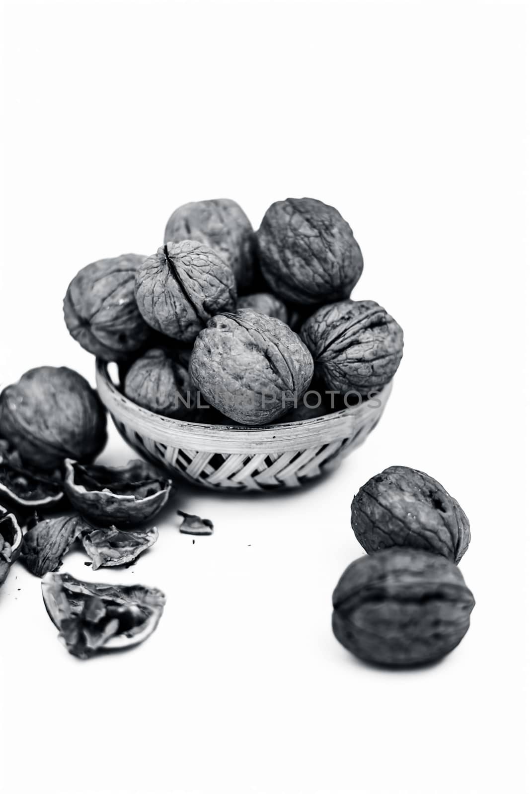Close up of essential oil or essence of walnut or akhrot isolated on white in a small transparent glass bottle along with raw in shell walnuts or Juglans.