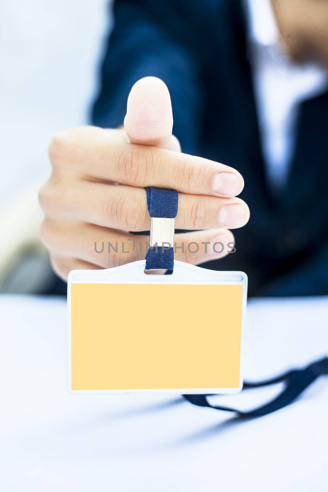 Close up of business man wearing blue colored suit and showing his identity card isolated on white.