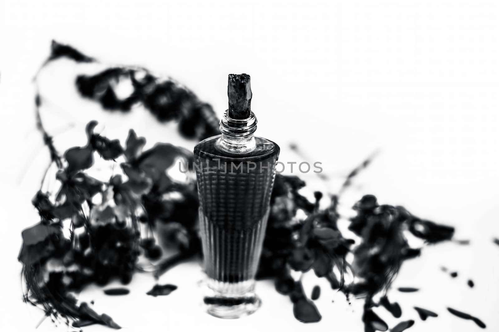 Close up shot of perfume or scent of peacock flower in a transparent bottle along with raw flowers isolated on white.