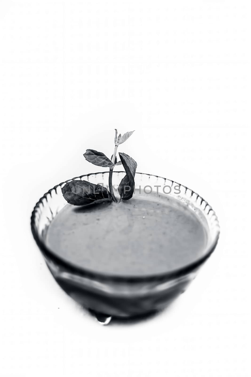 Close up shot of popular Indian sauce or chutney i.e. Phudina ki chutney isolated on white in a transparent glass bowl.