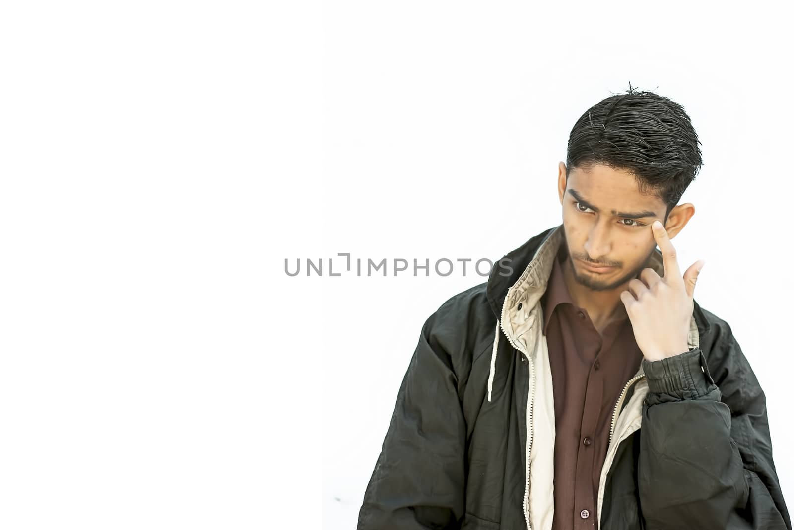 Portrait shot of a young beard man wearing brown colored shirt and a black colored jacket thinking seriously on a subject with one hand on the head pointing sign. by mirzamlk