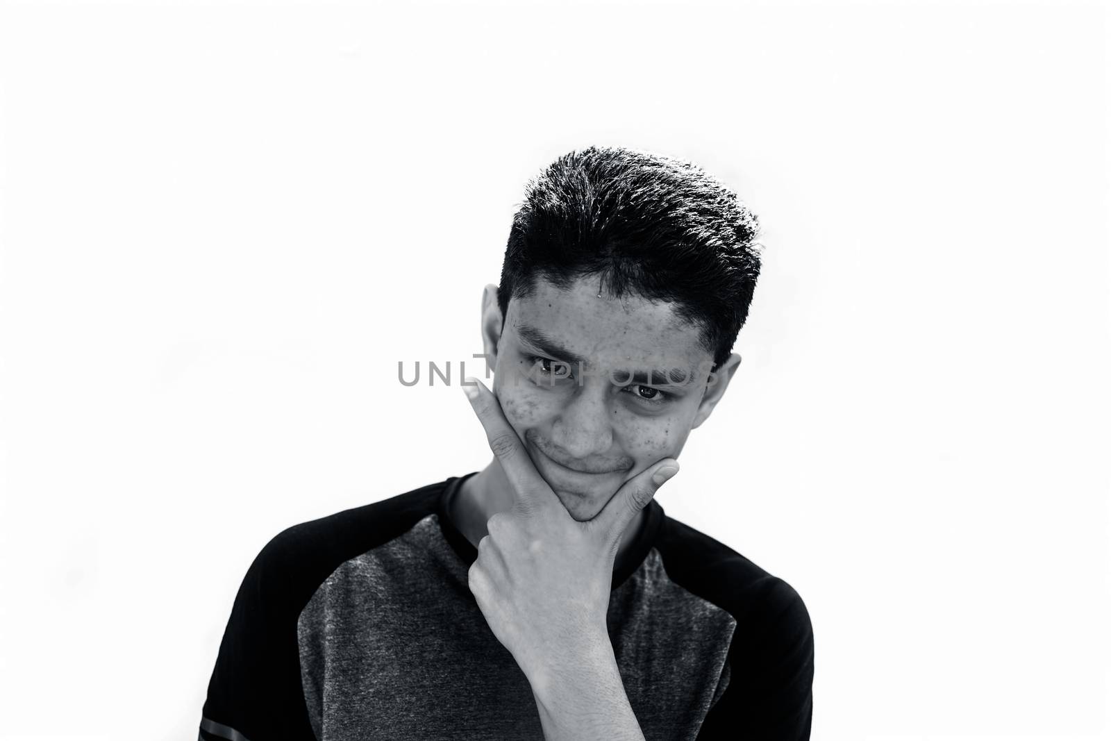 Portrait shot of young teenager or youngster isolated on white expressing some doubtfulness on his face wearing a Grey and black t shirt.