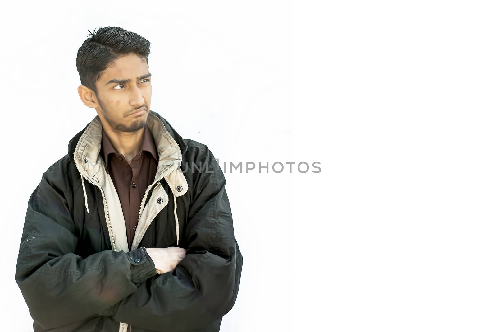 Portrait shot of a young beard man wearing brown colored shirt and a black colored jacket expressing curiousness by looking at the blank side.
