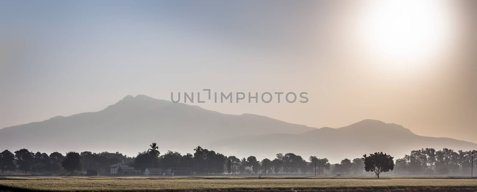 Wide landscape shot of sunrise through mountains in the early morning through fields with mist and fog. by mirzamlk