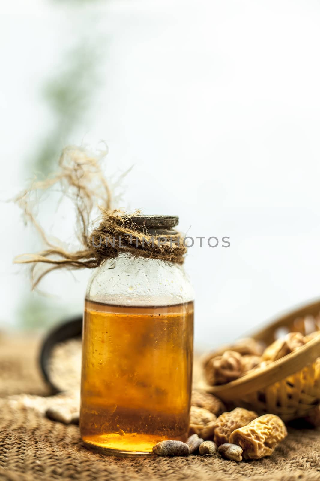 Close up of raw organic kharek or dried dates in a hamper or basket with its extracted herbal beneficial oil in a transparent bottle on gunny bag's surface.