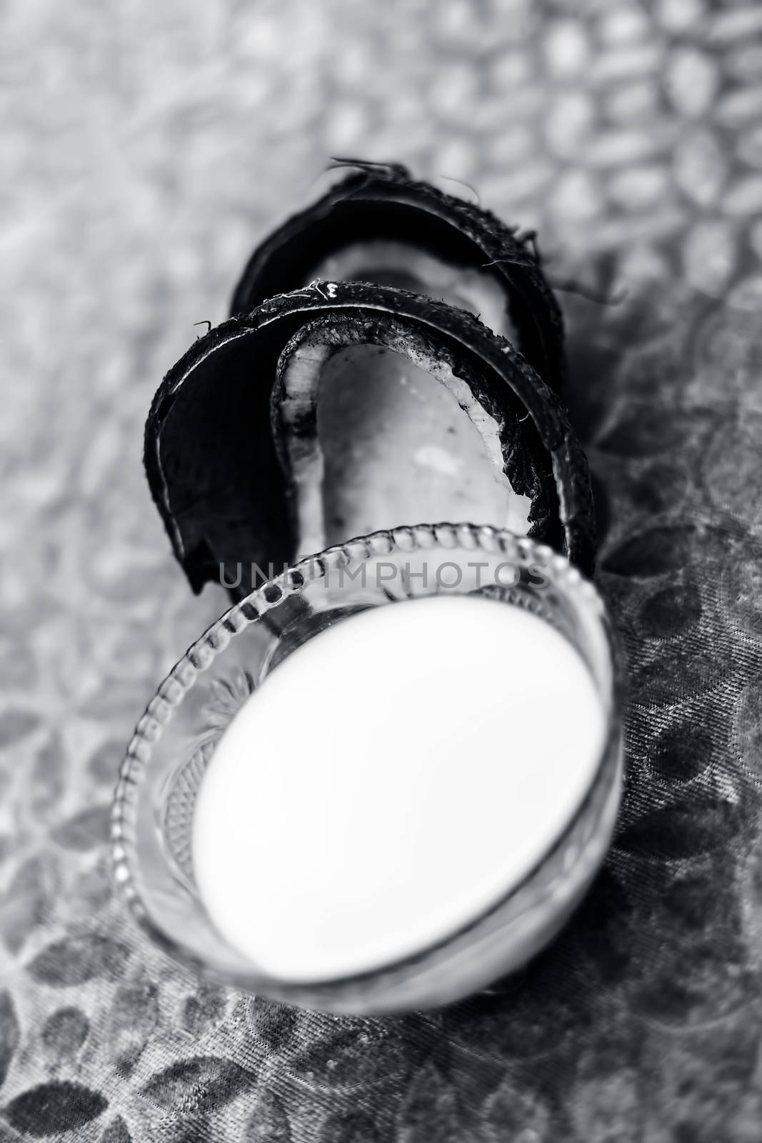 Close up of organic fresh coconut milk in a glass bowl with raw dried coconut isolated on brown colored surface.