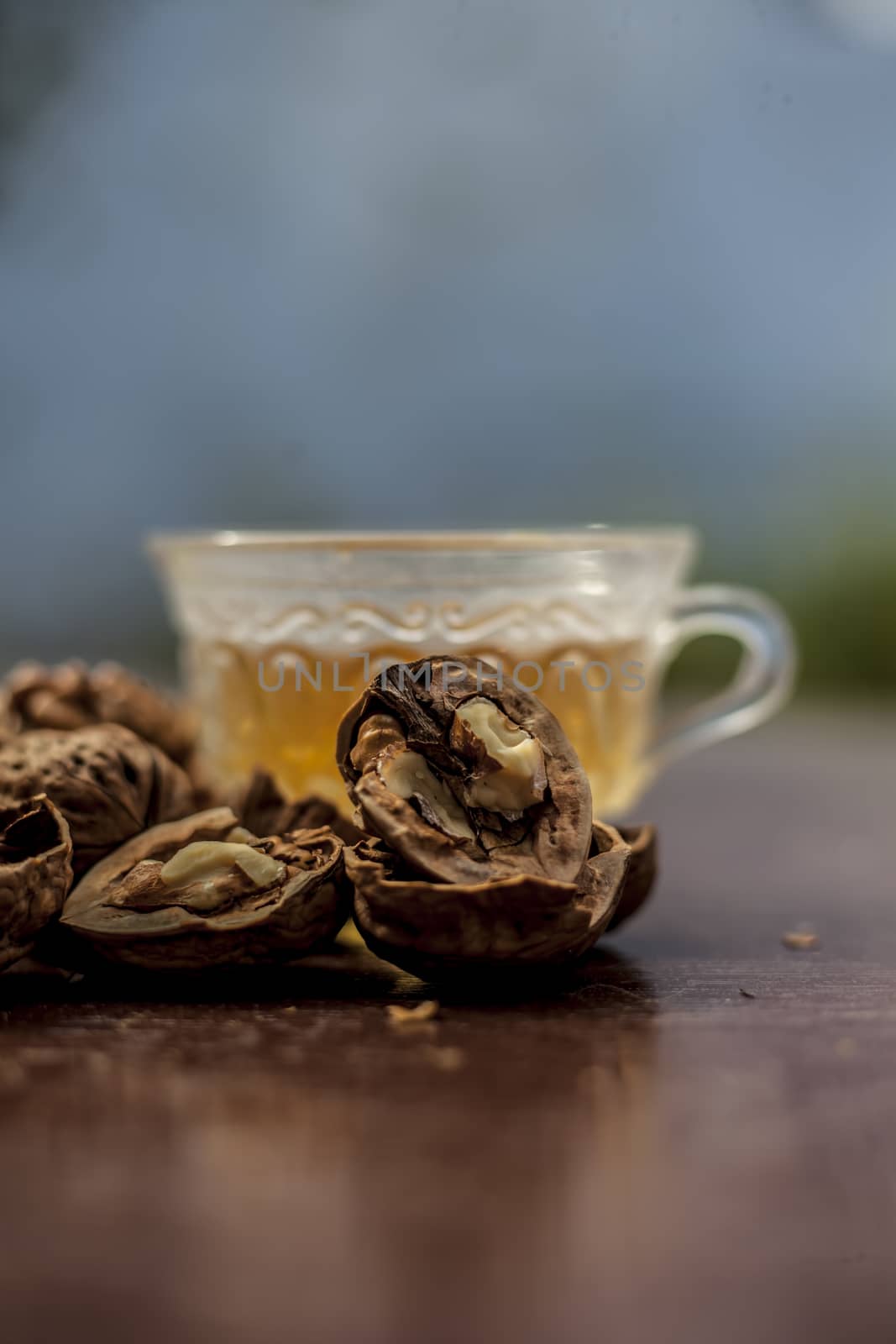 Close up of herbal organic tea of wall nut or walnut tea in a transparent glass cup with raw wall nut in shell and broken also.
