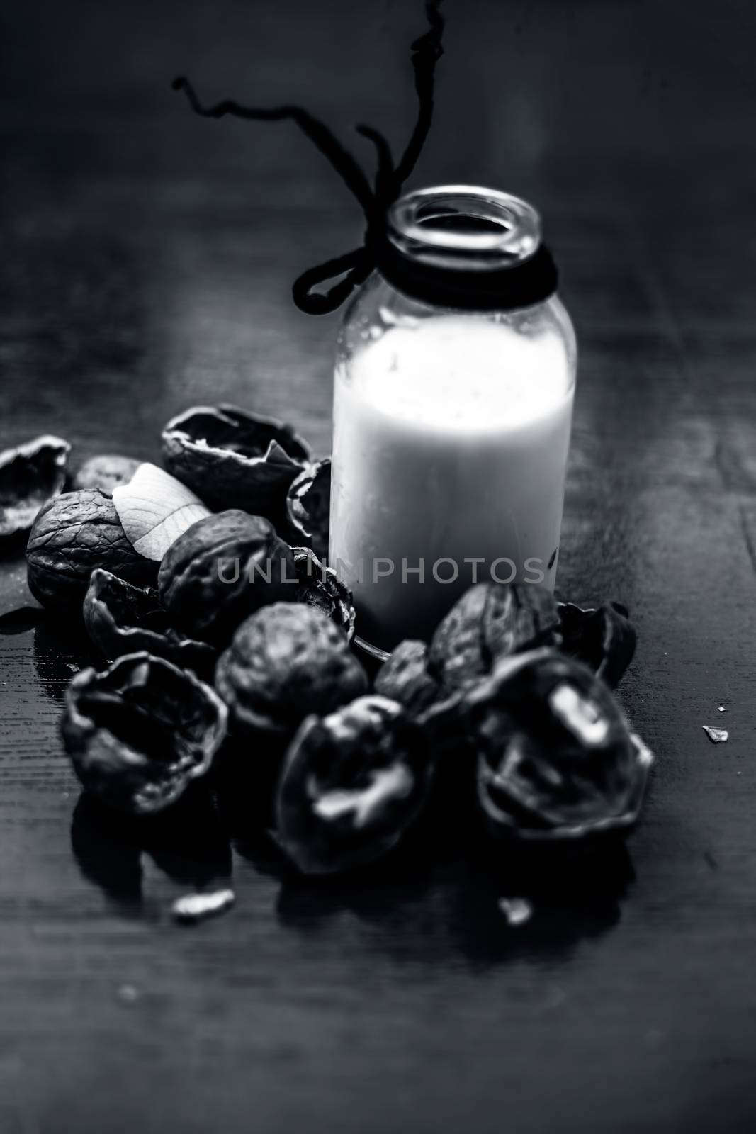 Close up of walnut or akhrot on wooden surface in a clay bowl with a small transparent bottle used to make dry fruit milkshake.