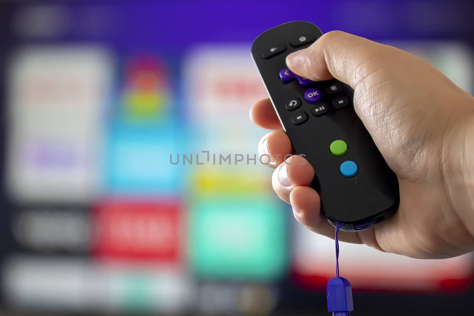 A person holding a digital media player remote control with a tv on the background by oasisamuel