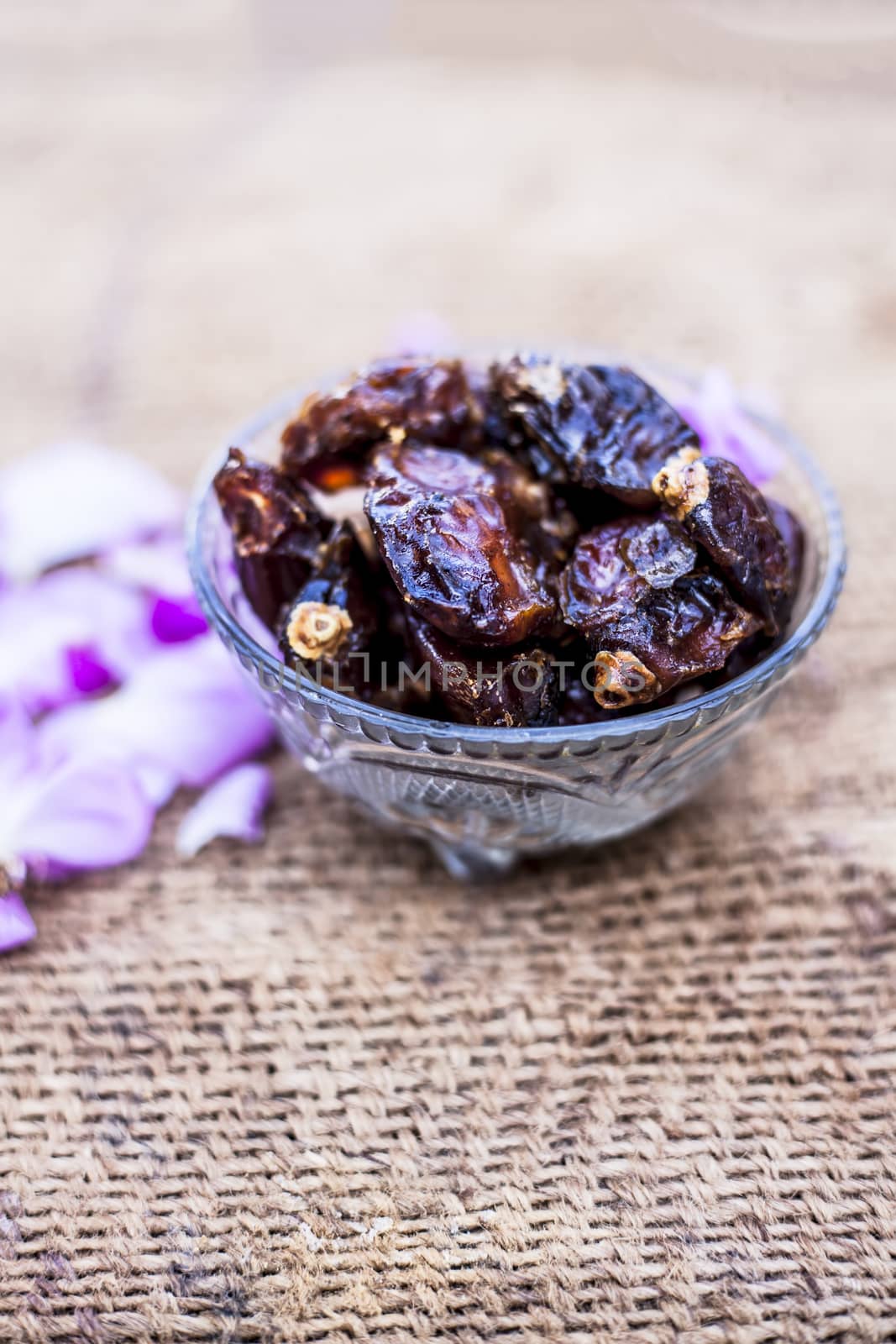 Close up of shot of raw organic dates or khajoor or Phoenix dactylifera in a glass bowl on a gunny bag background.