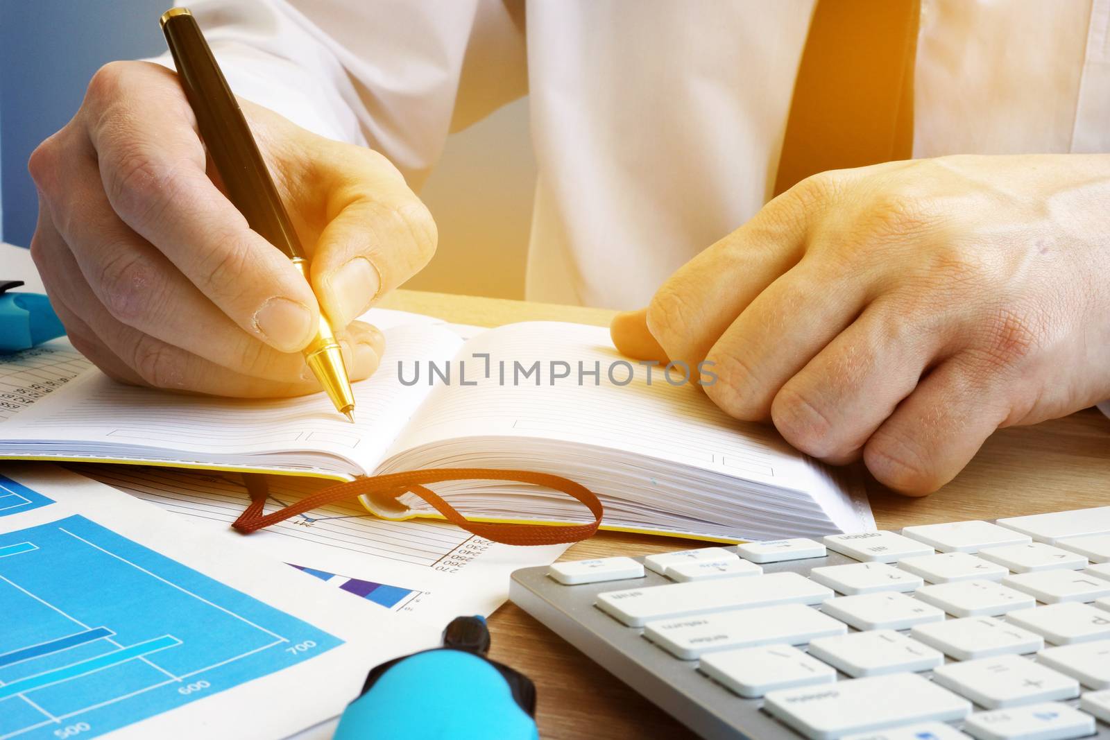 Businessman writing in a notepad. Workplace in the office.