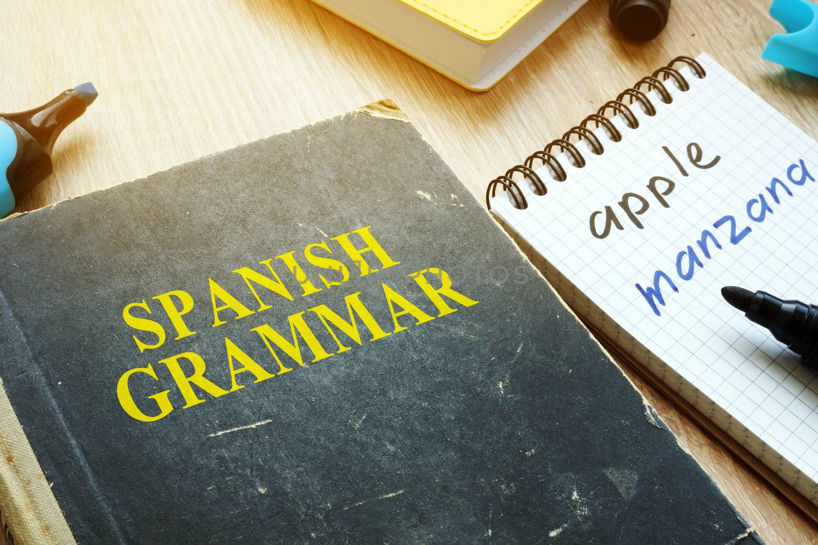 Learn Spanish grammar concept. Book and notebook on a desk.