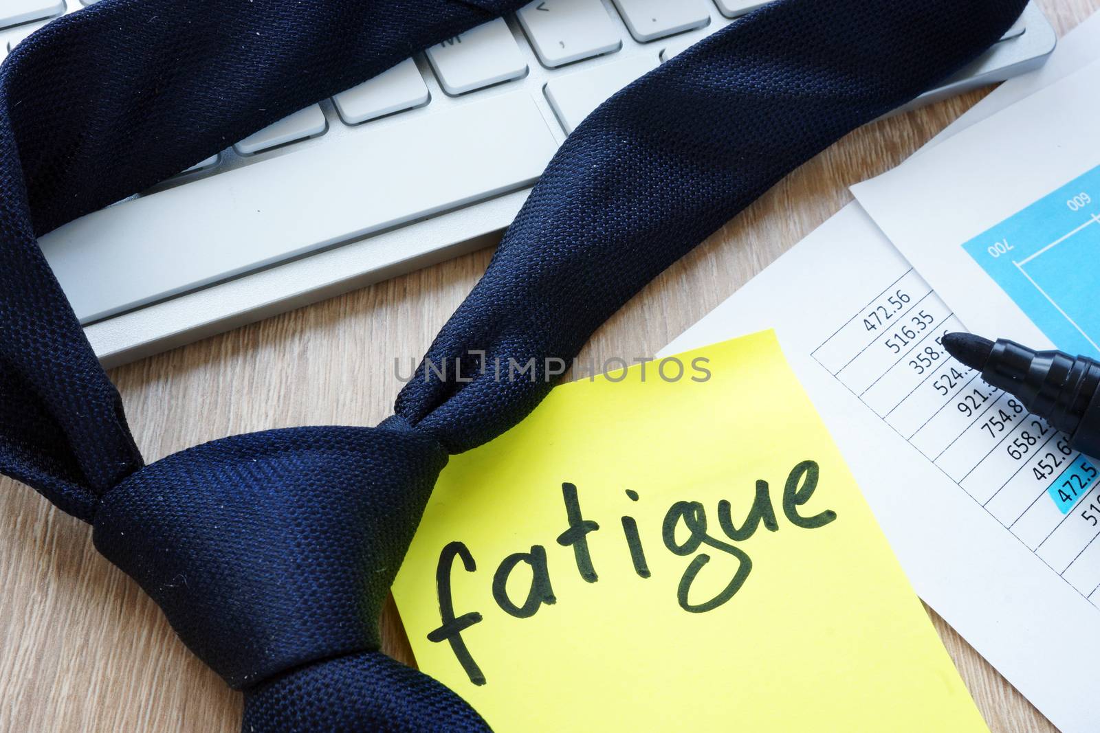 Tie and memo stick with word fatigue on an office desk.