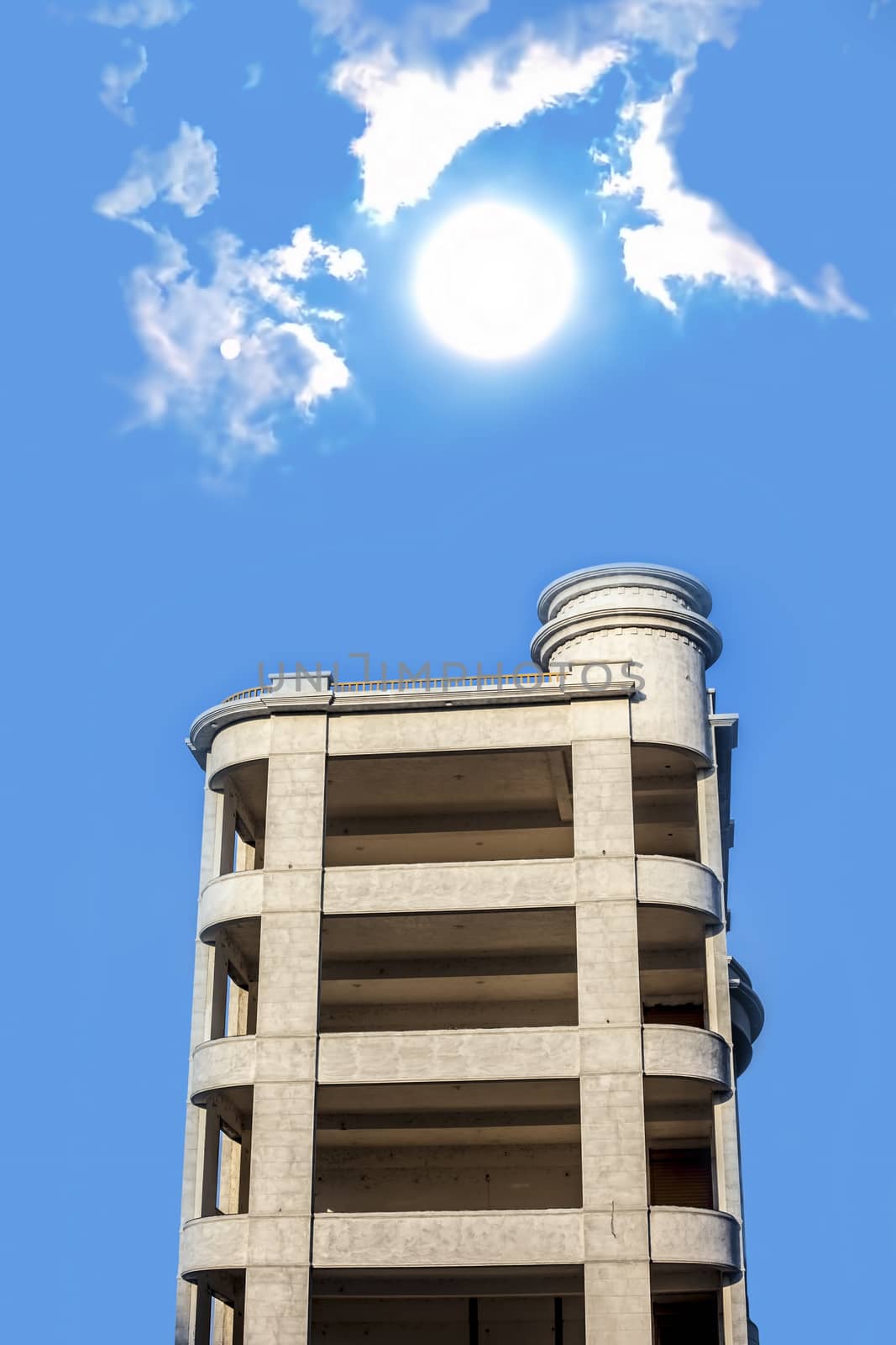 Architectural minimalistic shot of white colored building with sun and clouds.