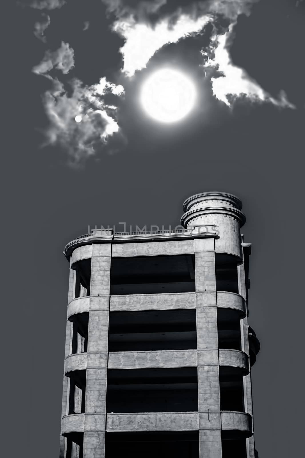 Architectural minimalistic shot of white colored building with sun and clouds.