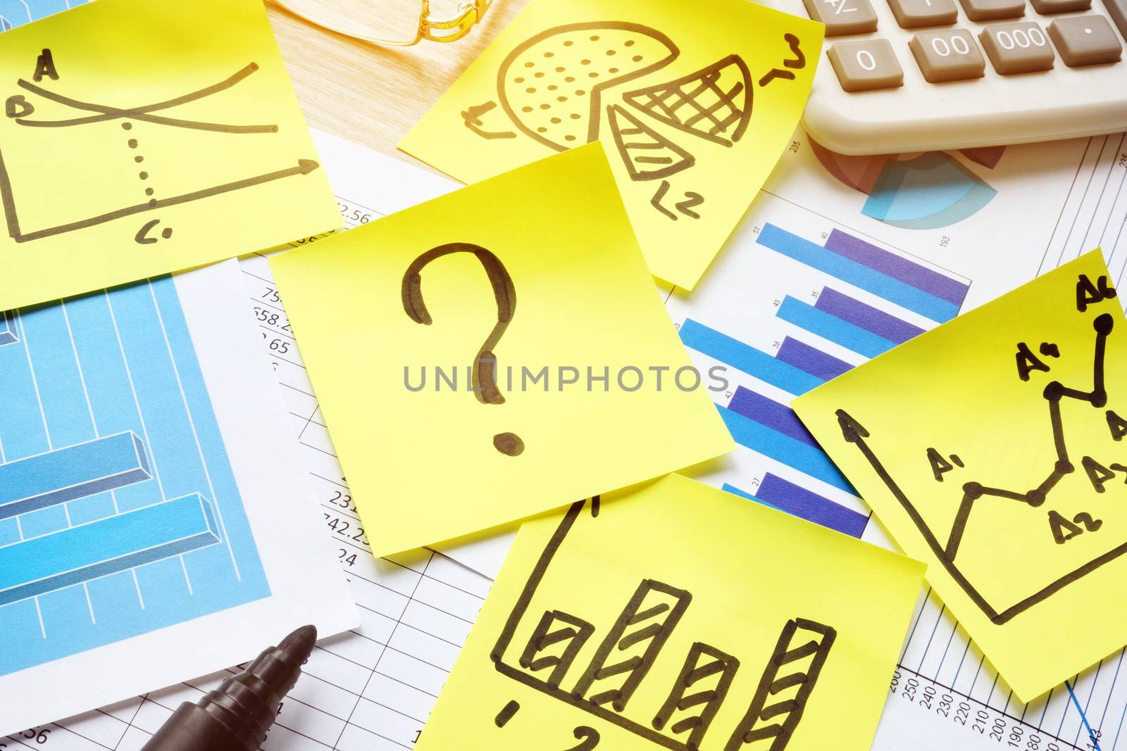 Question mark on stick, business papers and financial charts.