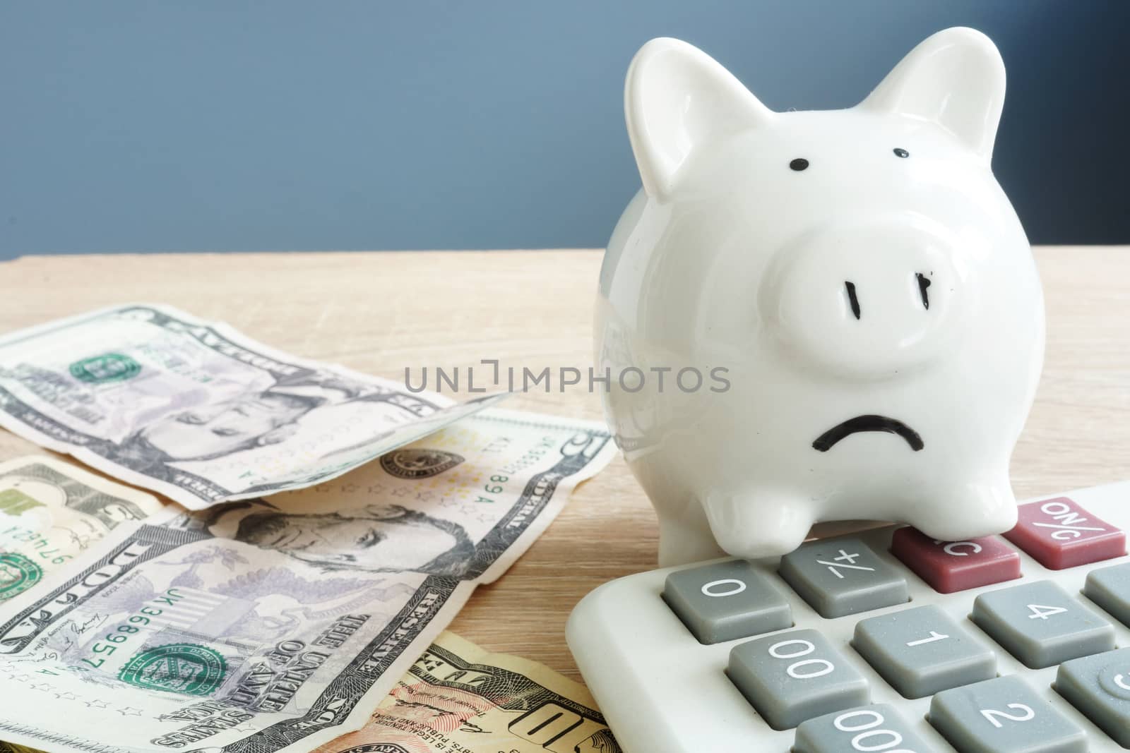 Money worries concept. Unhappy piggy and few banknotes with calculator. Problems with money.