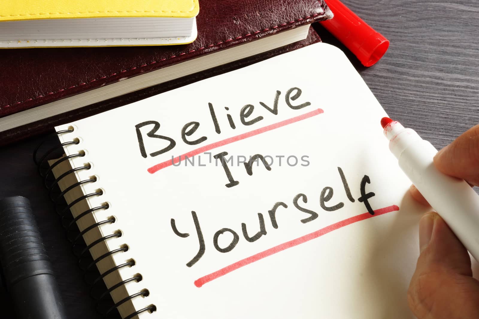 Man is writing Believe In Yourself in a note. Motivation.