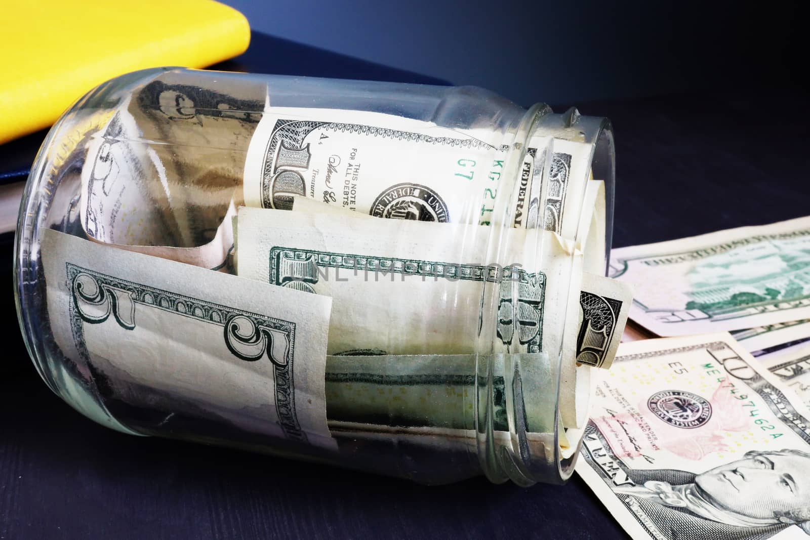 Savings. Jar with money. Dollar banknotes on a desk.