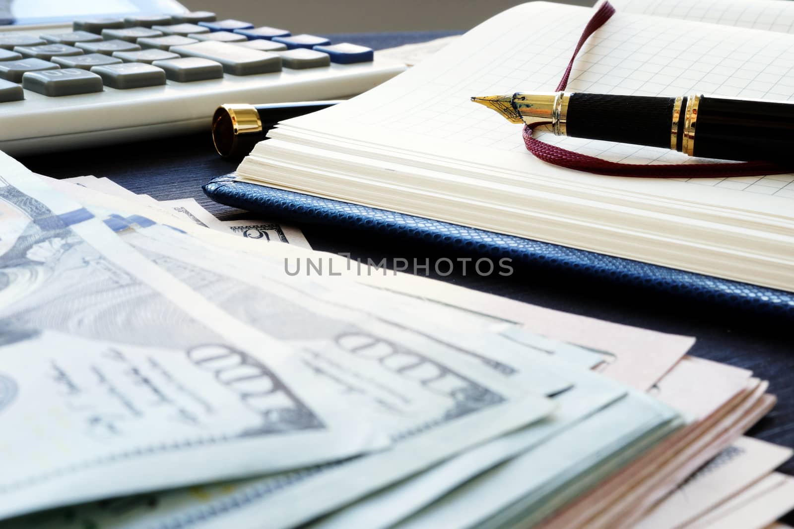 Small business accounting. Pile of money, note and pen.