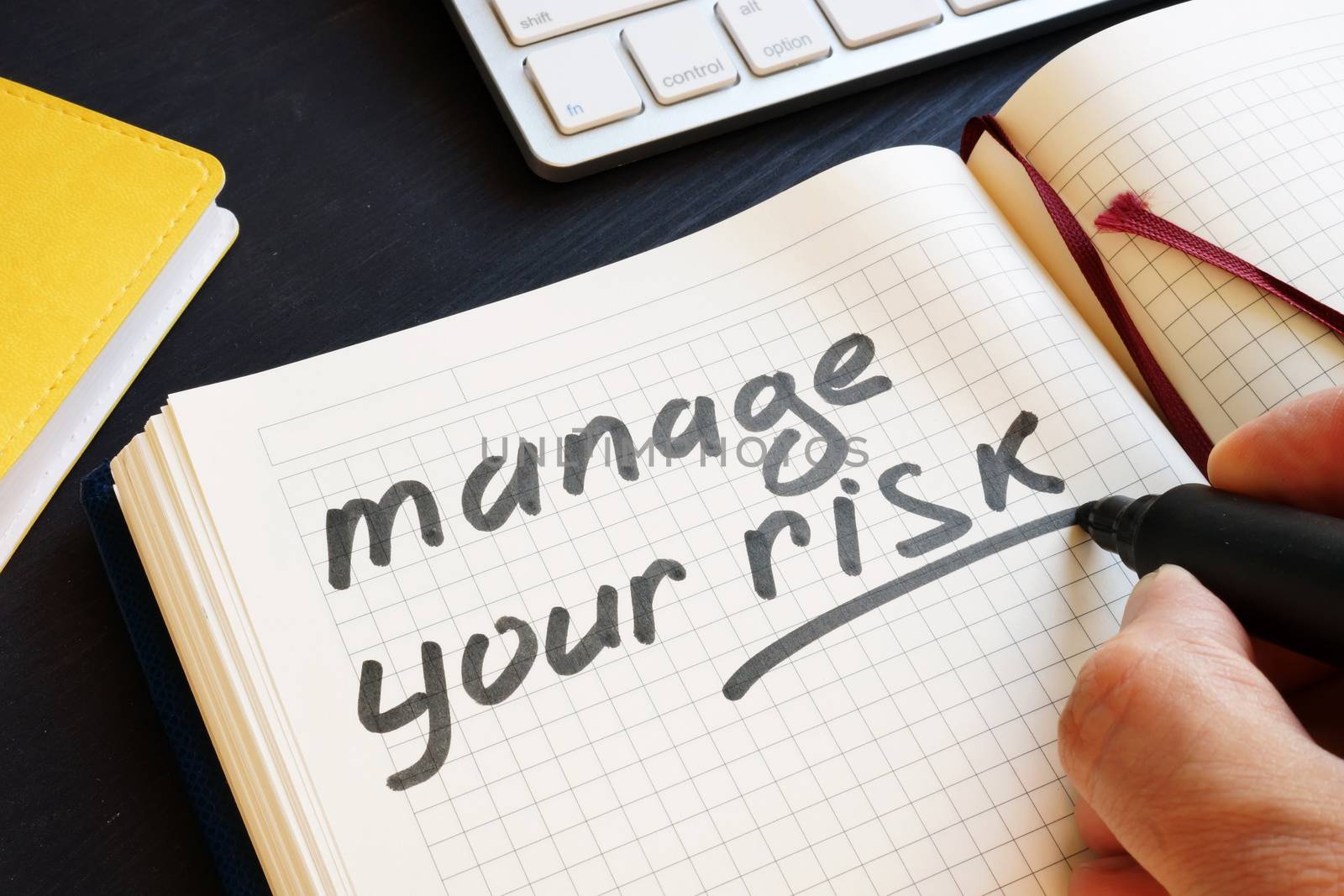 Man is writing manage your risk in a note.