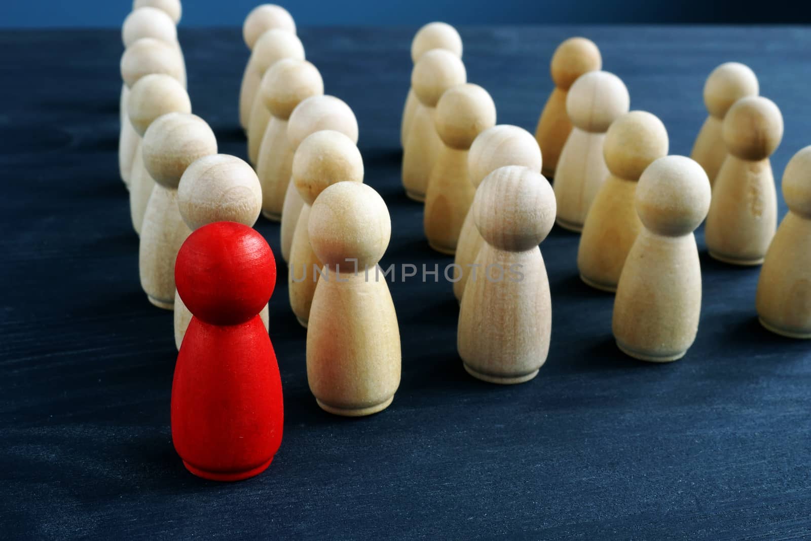 Leader or manager ahead of crowd. Figures from wood on a desk.