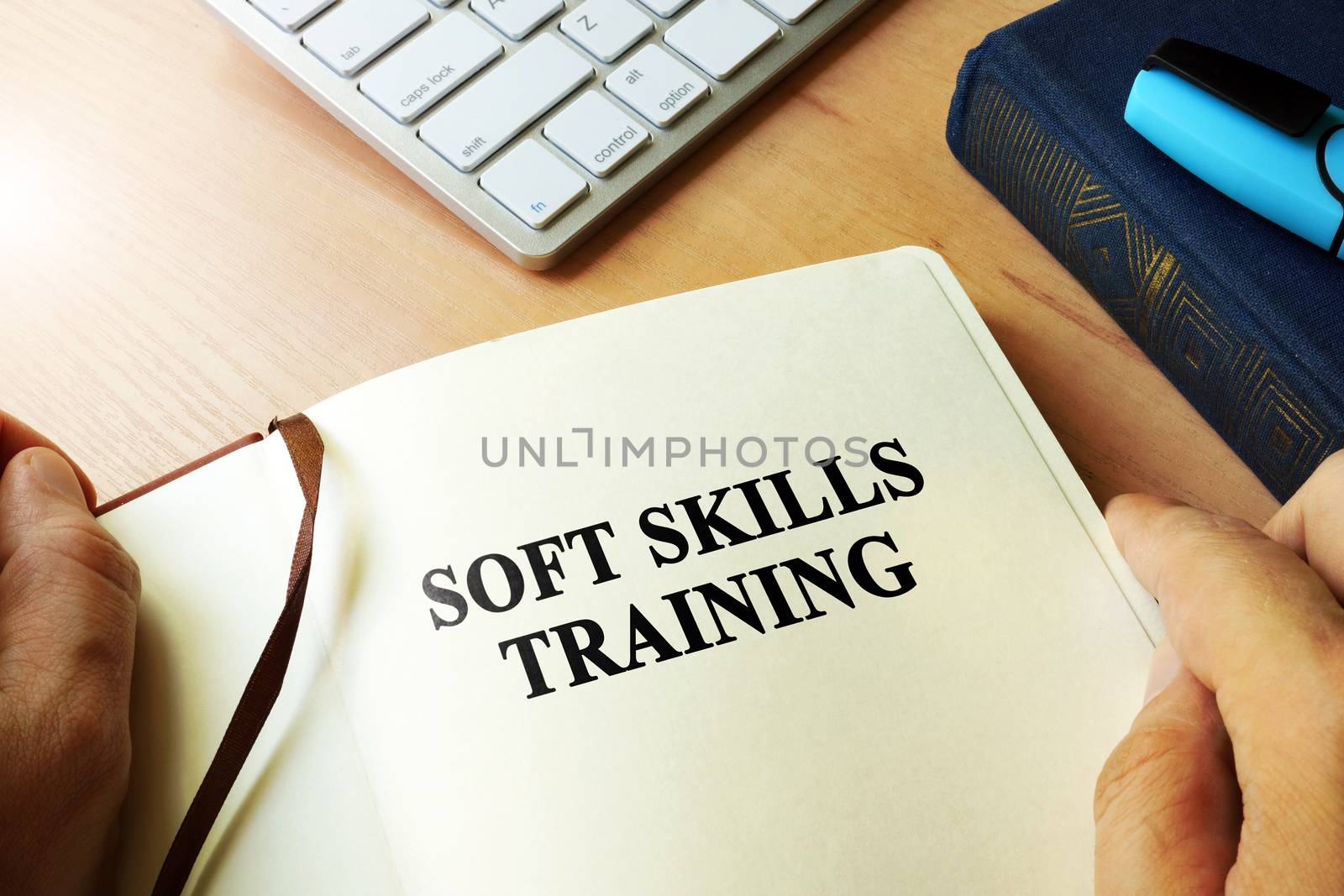 Hands holding book with title Soft skills training. by designer491
