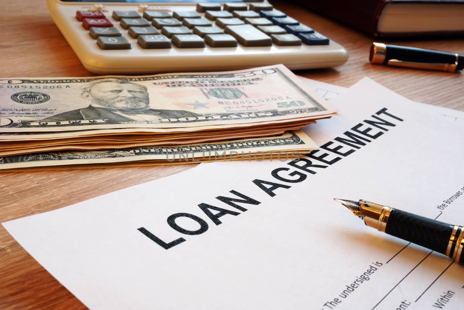 Loan agreement and dollar bills on an office desk.