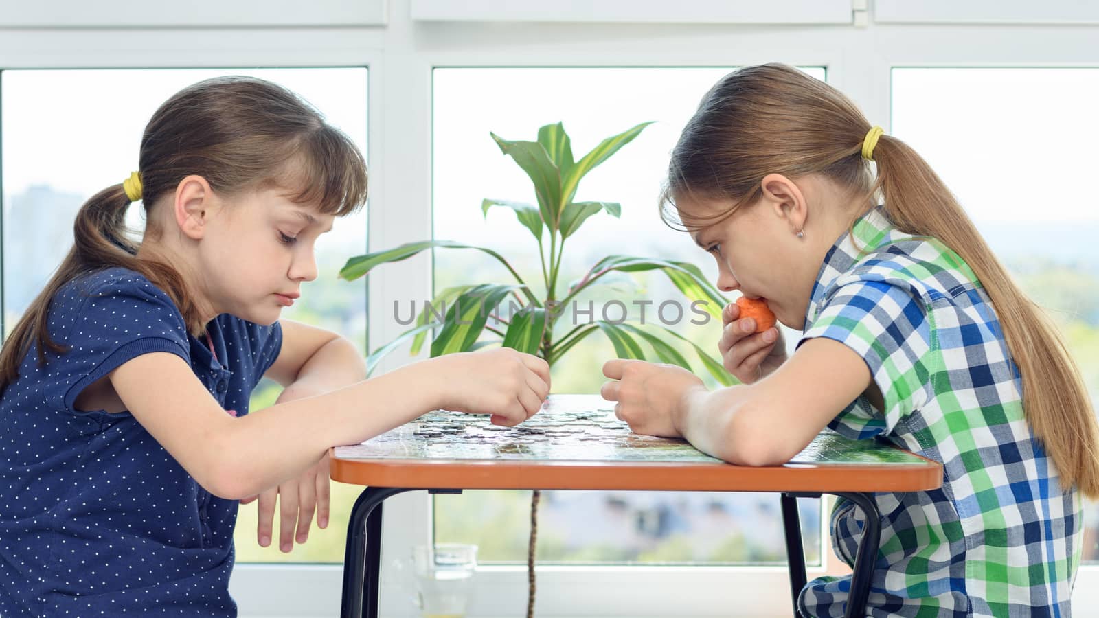 Children at home at the table collect puzzle puzzles