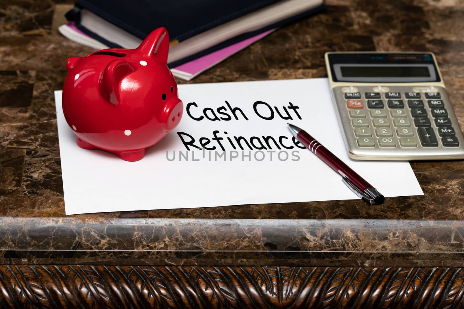 Paper with the words cash out refinancing on a table next to a red piggy Bank. by bonilook