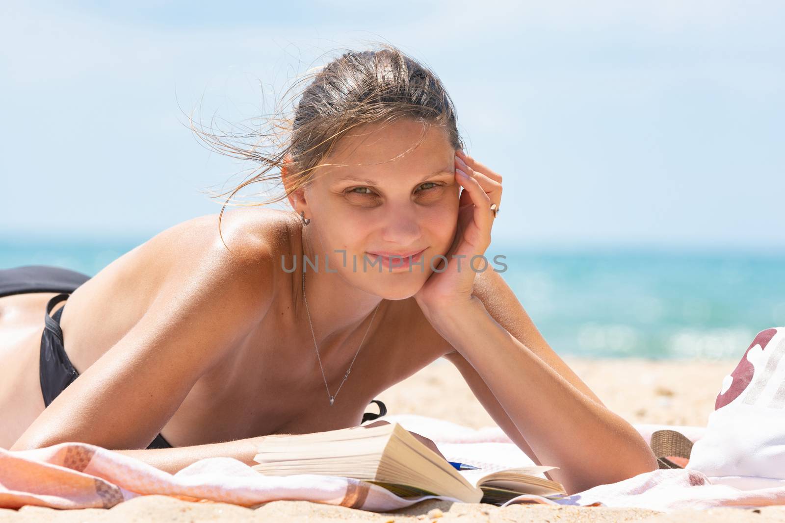 Relaxed girl sunbathes on the beach lying on the sand