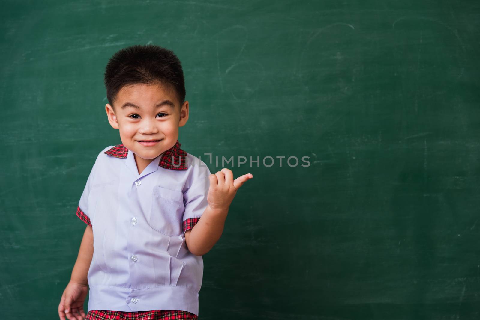 child from kindergarten in student uniform smiling on green scho by Sorapop