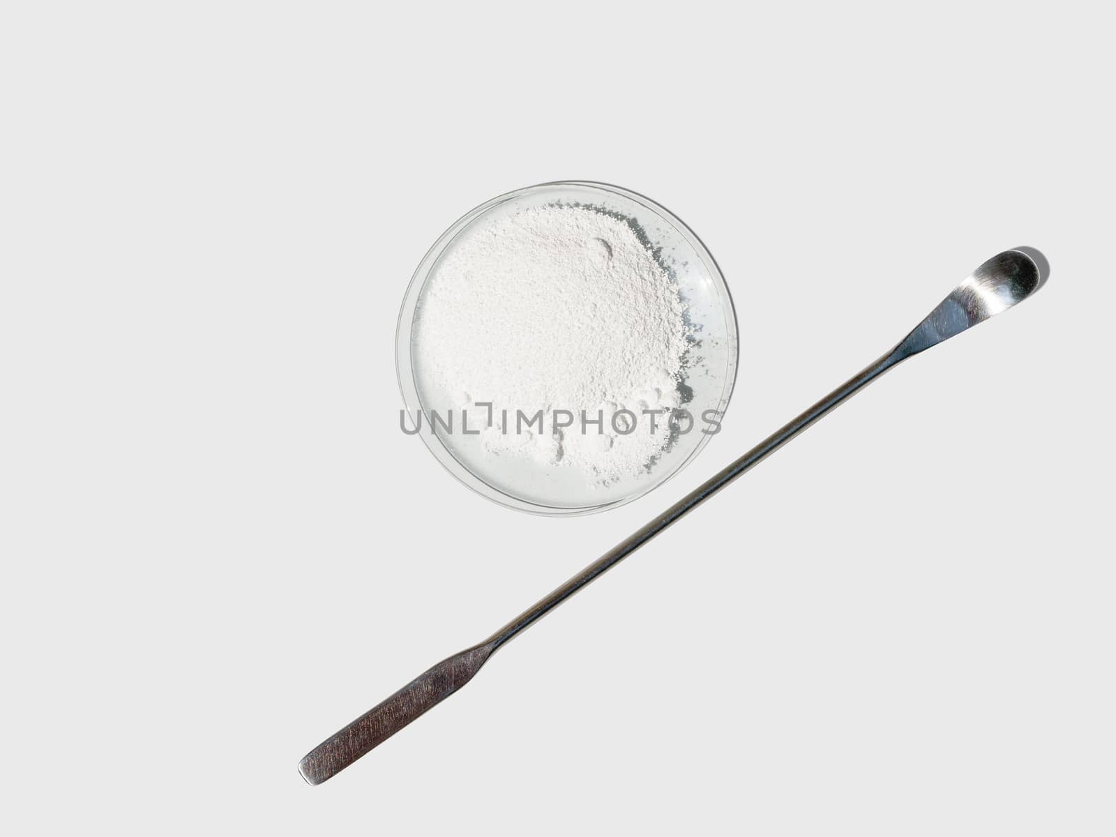 Polyacrylic acid powder in chemical watch glass placed next to the stirring rod on laboratory table.