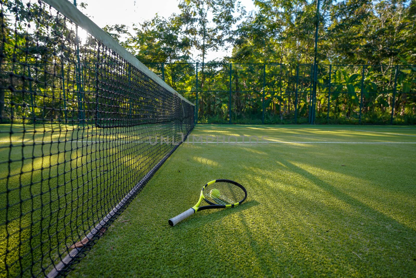 Tennis ball and racket in the artificial grass tennis court.