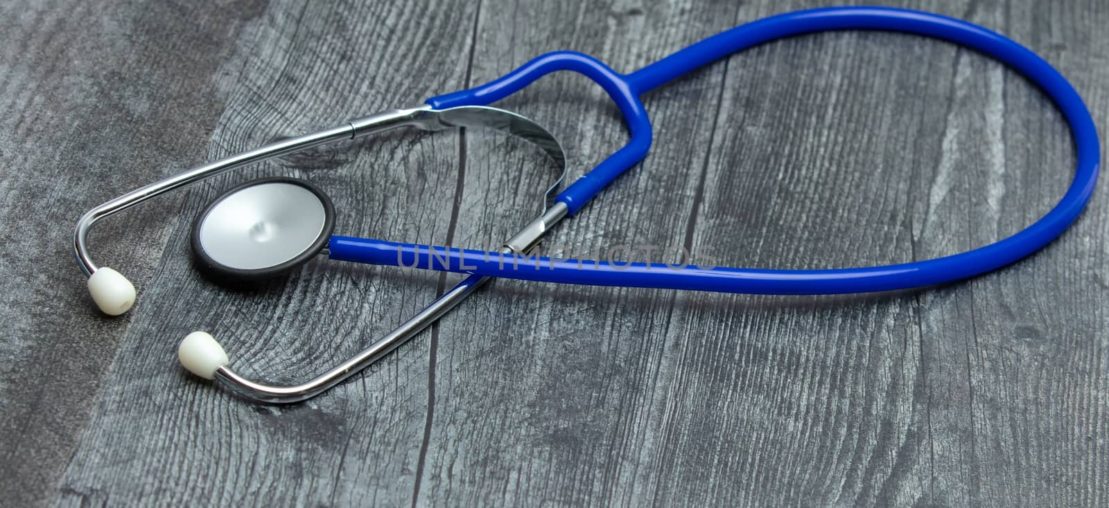 A blue medical stethoscope isolated on a wooden table.